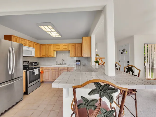 a kitchen with stainless steel appliances granite countertop a stove a sink dishwasher and a refrigerator with wooden floor