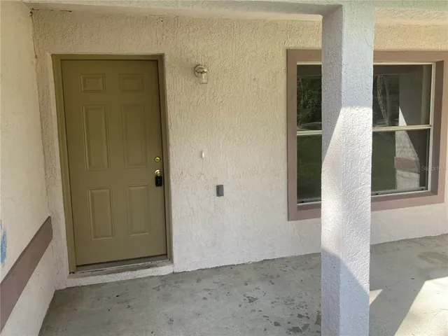 a view of an empty room with window and chandelier fan