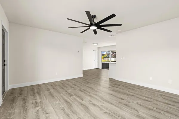 a view of empty room with wooden floor and ceiling fan