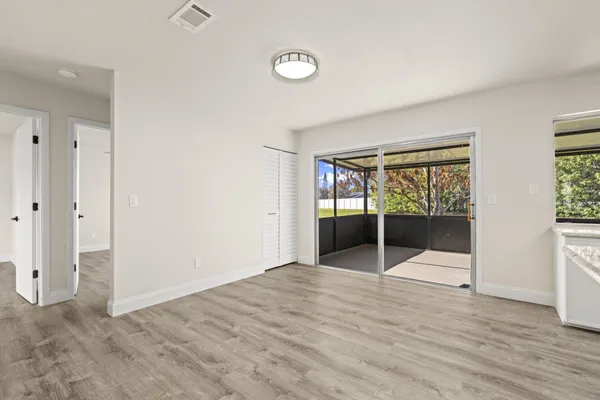an empty room with wooden floor and windows