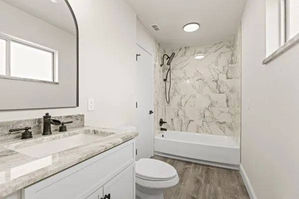 a bathroom with a granite countertop sink a toilet and shower
