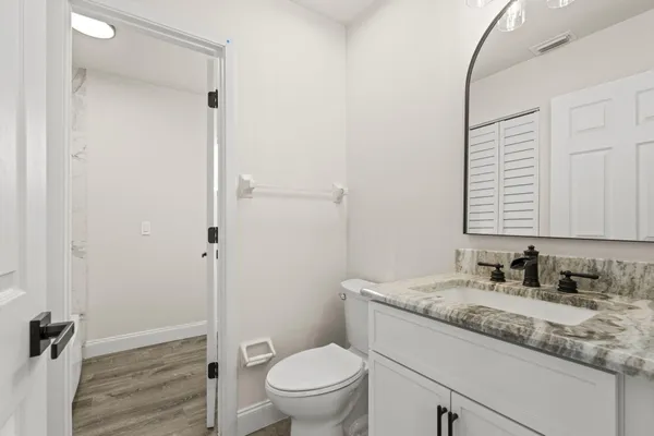 a bathroom with a granite countertop sink toilet a mirror and shower