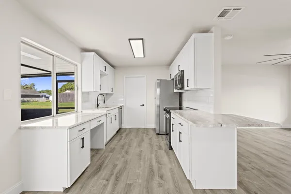 a large kitchen with a lot of counter space and wooden floor