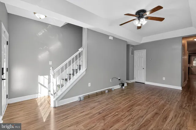 an empty room with wooden floor chandelier fan and windows