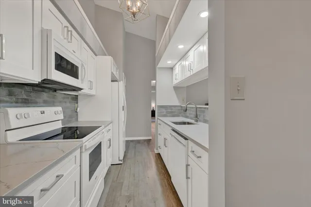 a kitchen with stainless steel appliances white cabinets and a stove top oven