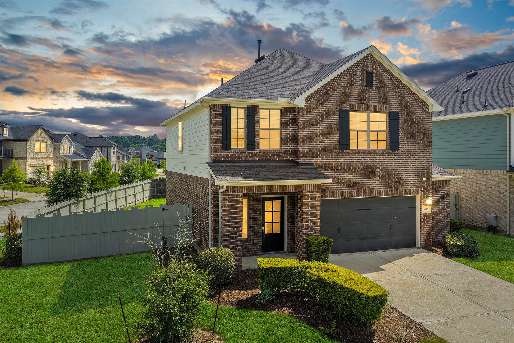 10603 Whitejacket Conroe, TX 77385 - Photo 2 of 42 This charming two-story brick house features a modern facade with a two-car garage and well-maintained landscaping. It sits in a picturesque neighborhood with a vibrant sunset backdrop, offering both curb appeal and a welcoming atmosphere.