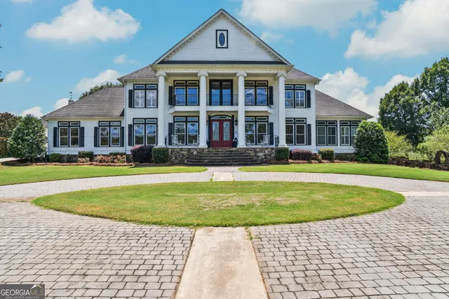 a view of a house with a big yard and large trees