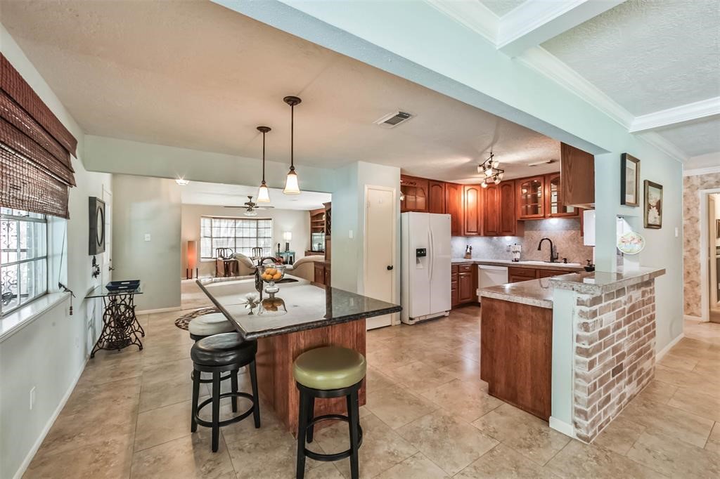 6911 Sprigg Street Fulshear, TX 77441 - Photo 11 of 48 a kitchen with stainless steel appliances kitchen island granite countertop a table chairs in it and a window