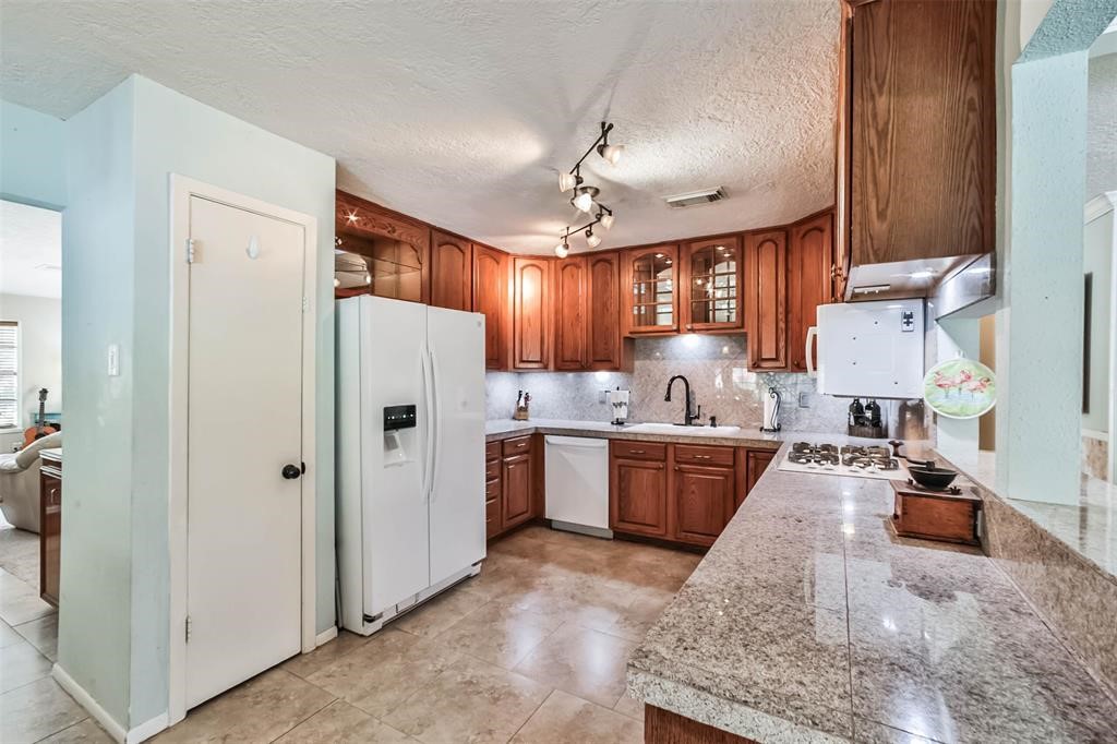 6911 Sprigg Street Fulshear, TX 77441 - Photo 13 of 48 a large white kitchen with cabinets a sink a window and a refrigerator