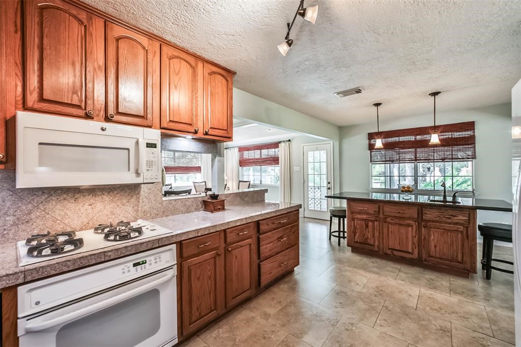 6911 Sprigg Street Fulshear, TX 77441 - Photo 15 of 48 a large kitchen with stainless steel appliances granite countertop wooden cabinets a sink dishwasher a stove and a refrigerator with wooden floor
