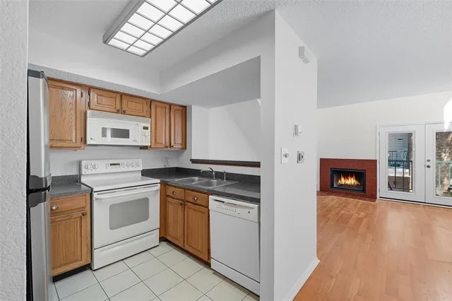 a kitchen with stainless steel appliances granite countertop a stove top oven a sink dishwasher and a refrigerator with wooden floor