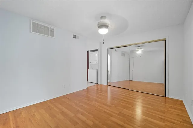 a view of an empty room with wooden floor and a bathroom