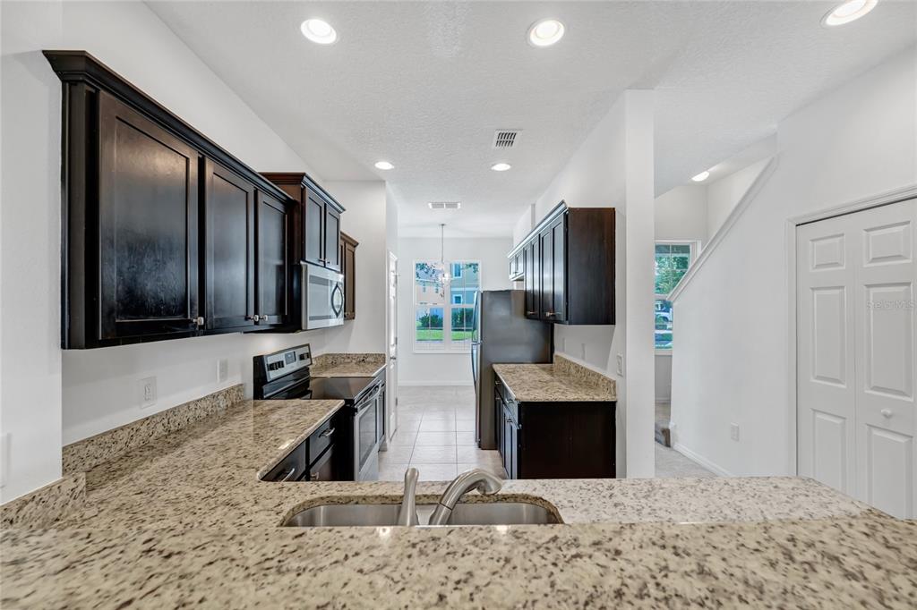 4824 Poolside Drive St. Cloud, FL 34769 - Photo 7 of 29 a view of kitchen with stainless steel appliances kitchen island granite countertop a refrigerator and a sink