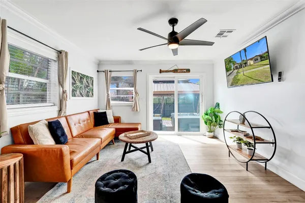 a living room with furniture a ceiling fan and a large window