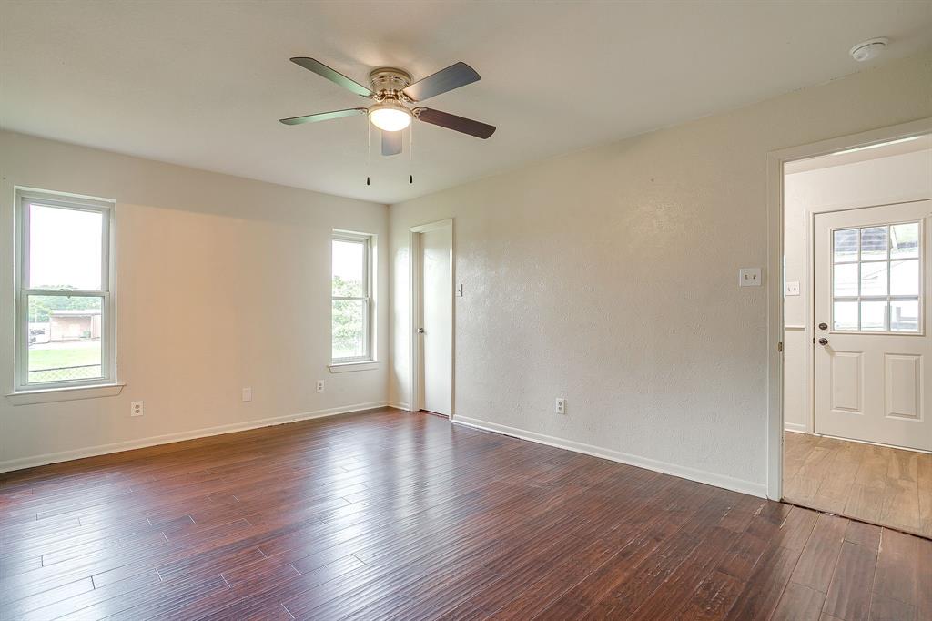 709 North Ave B Springtown, TX 76082 - Photo 23 of 32 an empty room with wooden floor chandelier fan and windows