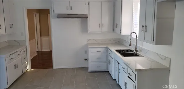 a kitchen with granite countertop white cabinets white appliances and a sink