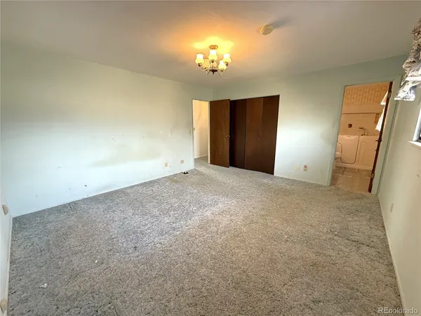 an empty room with a chandelier fan and windows