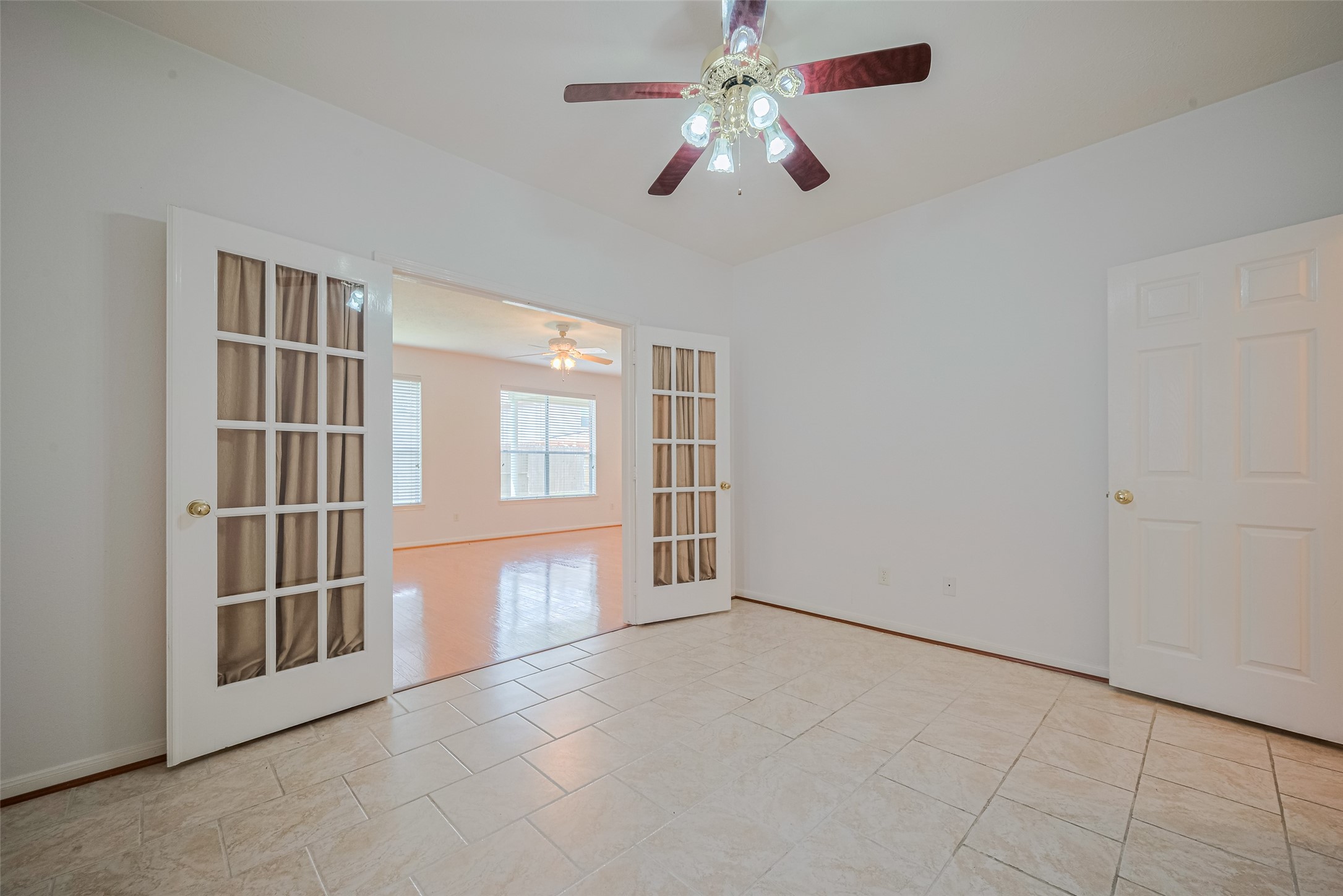 9218 Memorial Pines Way Spring, TX 77379 - Photo 18 of 39 Bright Office/Study room with tiled flooring and a ceiling fan, featuring French doors that lead to family room and a private exit and half bath on the other door. Ideal for flexible living or office space.