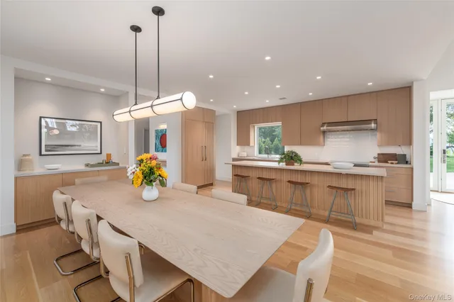 a kitchen with stainless steel appliances granite countertop a stove top oven a dining table and chairs with wooden floor