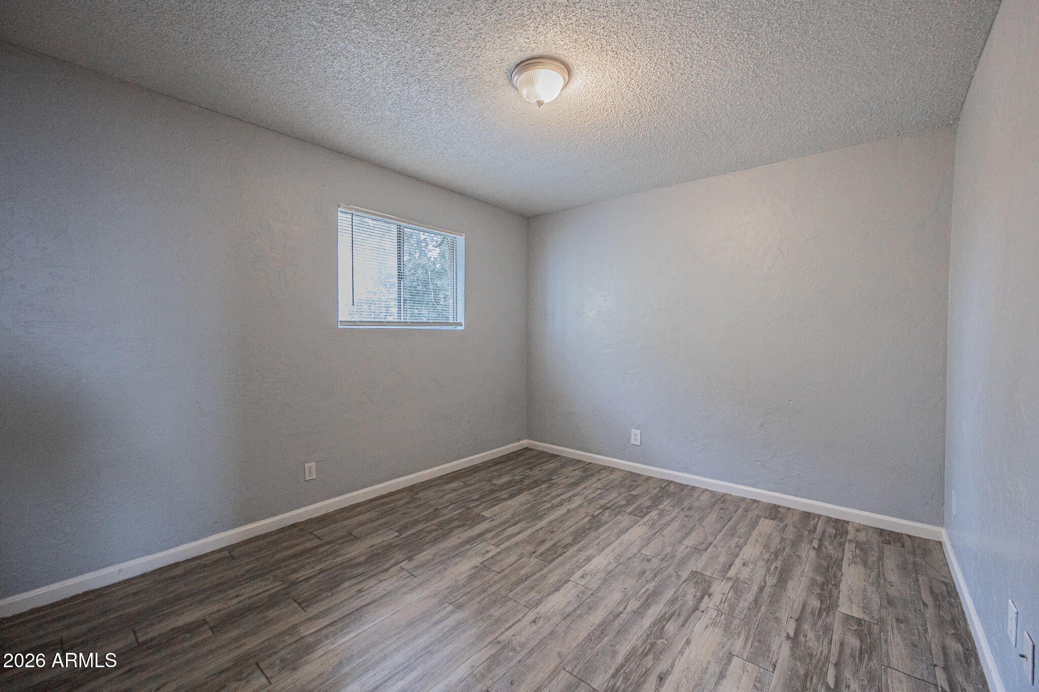 4615 North 39th Avenue, Unit 24 Phoenix, AZ 85019 - Photo 11 of 17 an empty room with wooden floor and windows