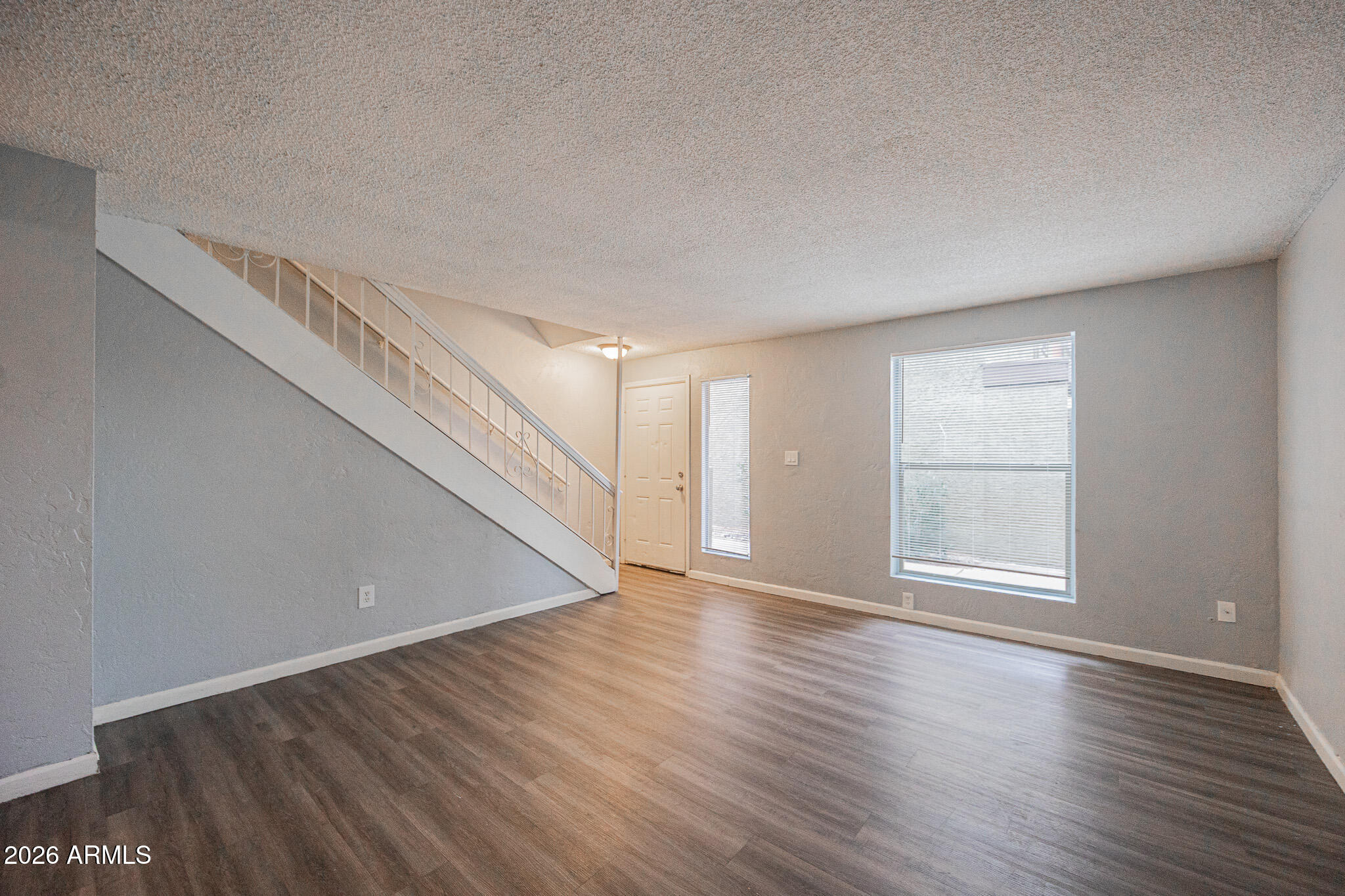 4615 North 39th Avenue, Unit 24 Phoenix, AZ 85019 - Photo 5 of 17 a view of an empty room with wooden floor and stairs