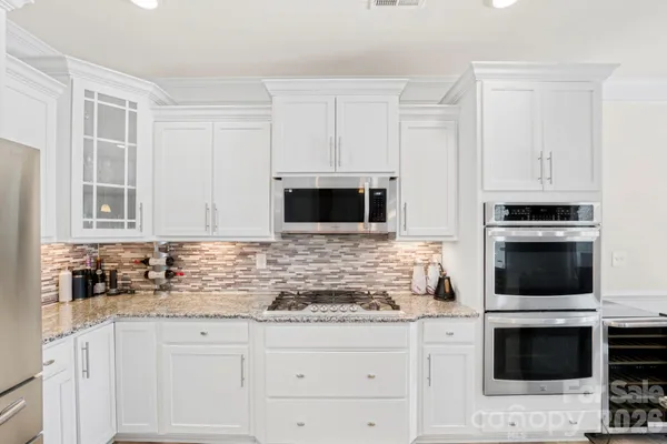 a kitchen with granite countertop white cabinets and stainless steel appliances