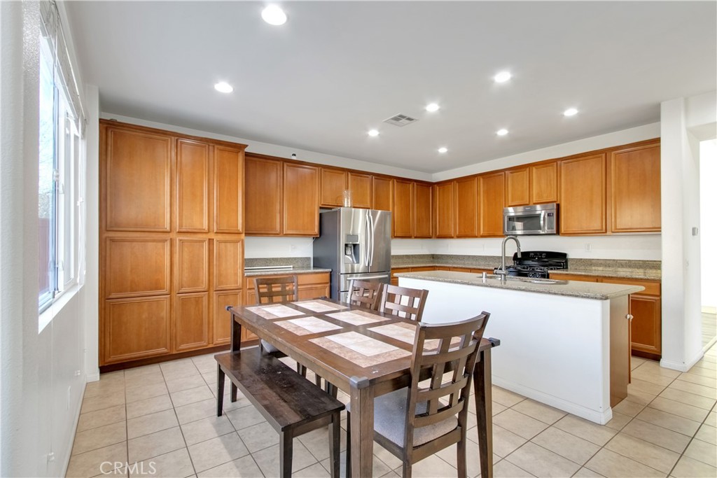 34020 Crenshaw Street Beaumont, CA 92223 - Photo 3 of 36 a kitchen with a refrigerator a stove a sink dishwasher with a dining table and chairs with wooden floor