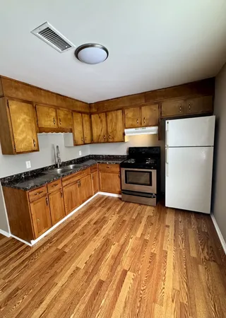 a kitchen with granite countertop a stove a sink and a refrigerator