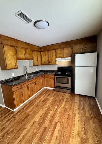 a kitchen with granite countertop a stove a sink and a refrigerator