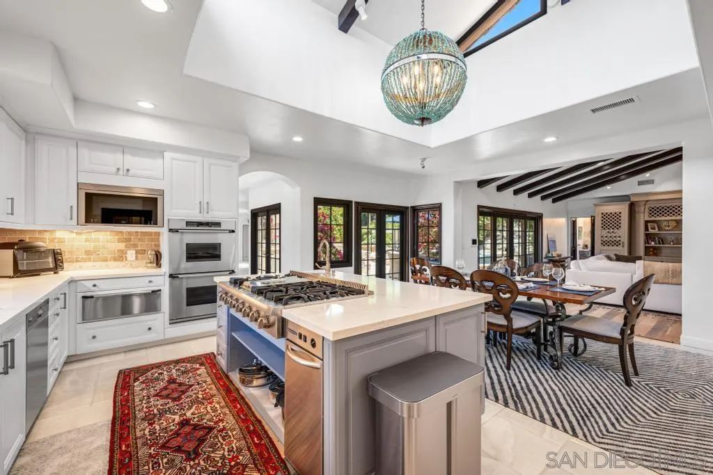 2643 Hidden Valley Road La Jolla, CA 92037 - Photo 31 of 61 a kitchen with stainless steel appliances granite countertop a stove top oven a sink a dining table and chairs with wooden floor
