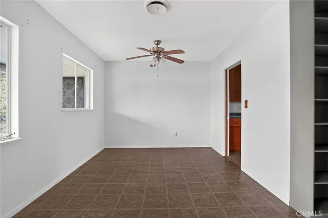 an empty room with chandelier fan and windows