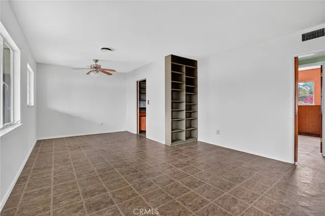 an empty room with windows and fan