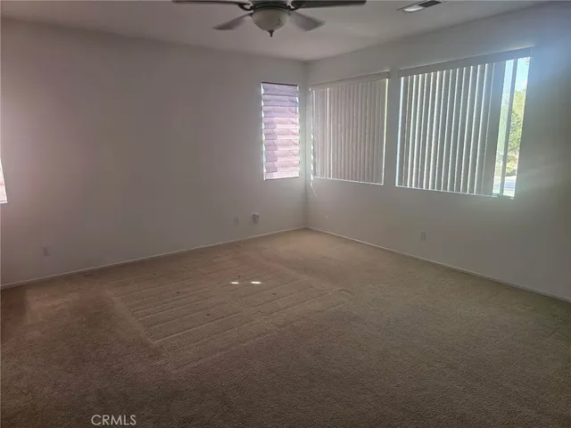 an empty room with windows and fan