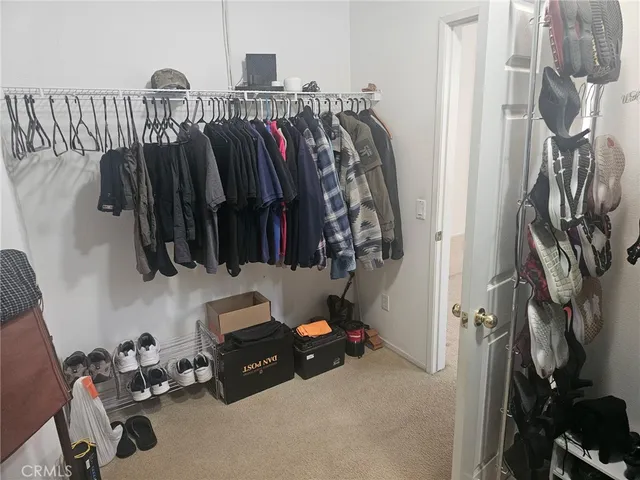 a view of walk in closet with clothes and shoes