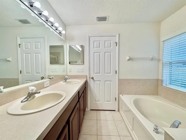 a bathroom with a tub sink and mirror