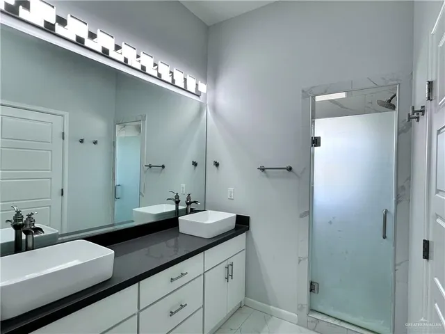 a spacious bathroom with a double vanity sink a mirror and shower