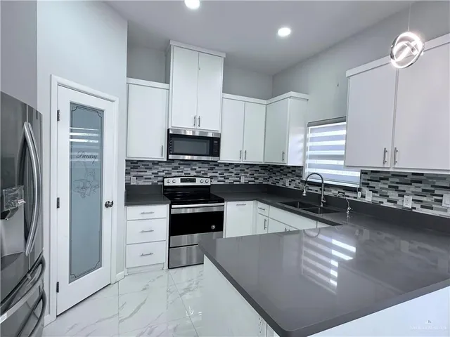 a kitchen with stainless steel appliances granite countertop a refrigerator a stove and a sink