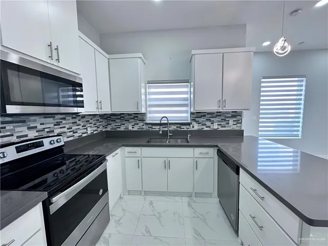 a kitchen with granite countertop a sink stove and cabinets
