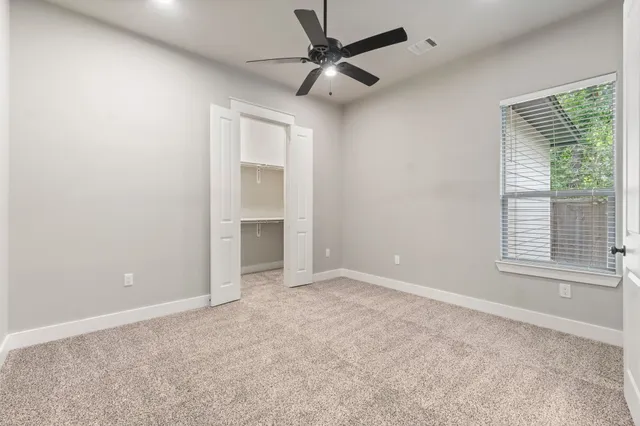 an empty room with fan and windows