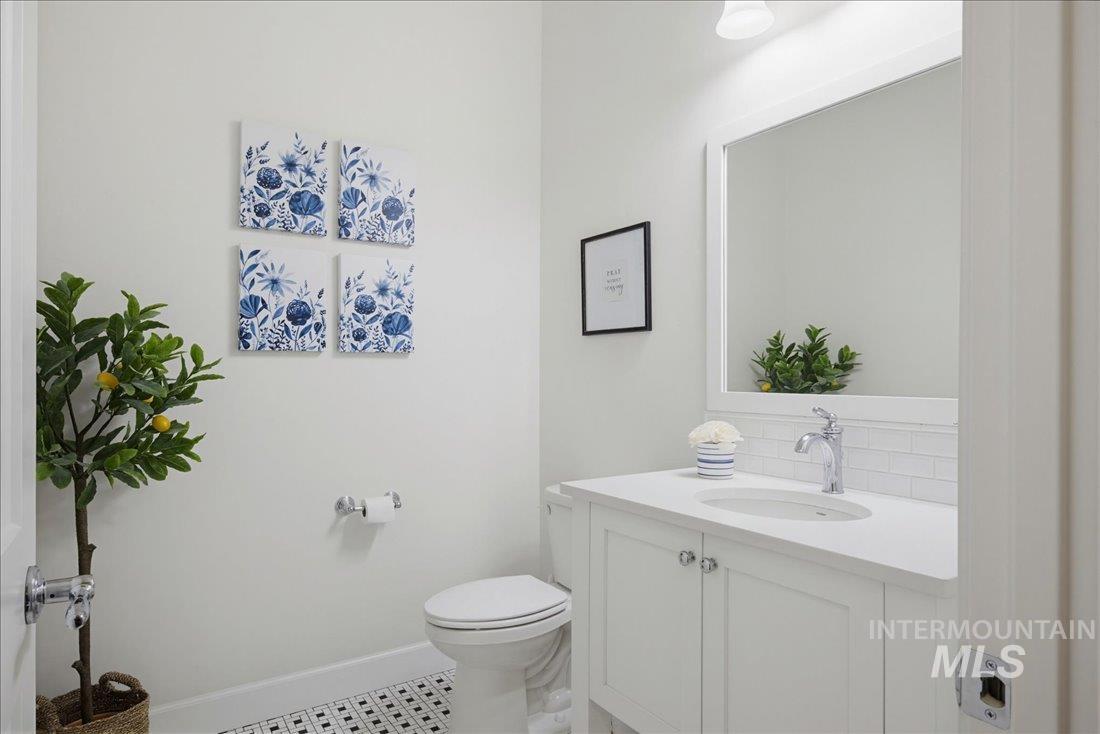 939 South Lake Pointe Way Eagle, ID 83616 - Photo 16 of 50 Bathroom featuring a white vanity with an integrated sink, polished chrome faucet, subway tile backsplash, and a framed mirror