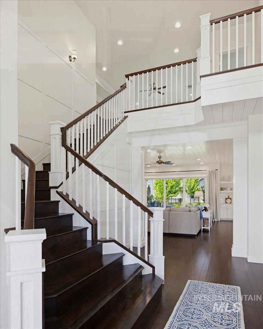 939 South Lake Pointe Way Eagle, ID 83616 - Photo 21 of 50 Grand two-story foyer featuring dark wood-finish flooring, white paneled walls, and a prominent staircase with white balusters and dark wood handrails