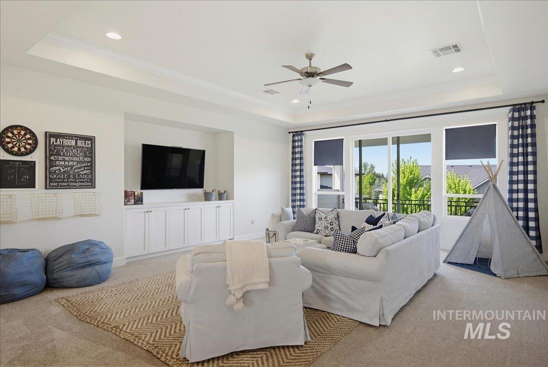 939 South Lake Pointe Way Eagle, ID 83616 - Photo 22 of 50 Tray ceiling with recessed lighting and a ceiling fan, built-in media center with white cabinetry, large windows with black solar shades, and carpeted flooring with a woven area rug