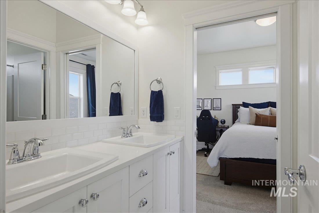 939 South Lake Pointe Way Eagle, ID 83616 - Photo 29 of 50 Double vanity with chrome faucets, white subway tile backsplash, and overhead vanity lighting