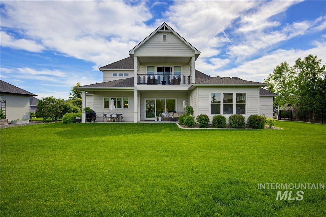 939 South Lake Pointe Way Eagle, ID 83616 - Photo 33 of 50 Expansive green lawn bordering a two-story residence with a covered patio, upper-level balcony, and multiple large windows