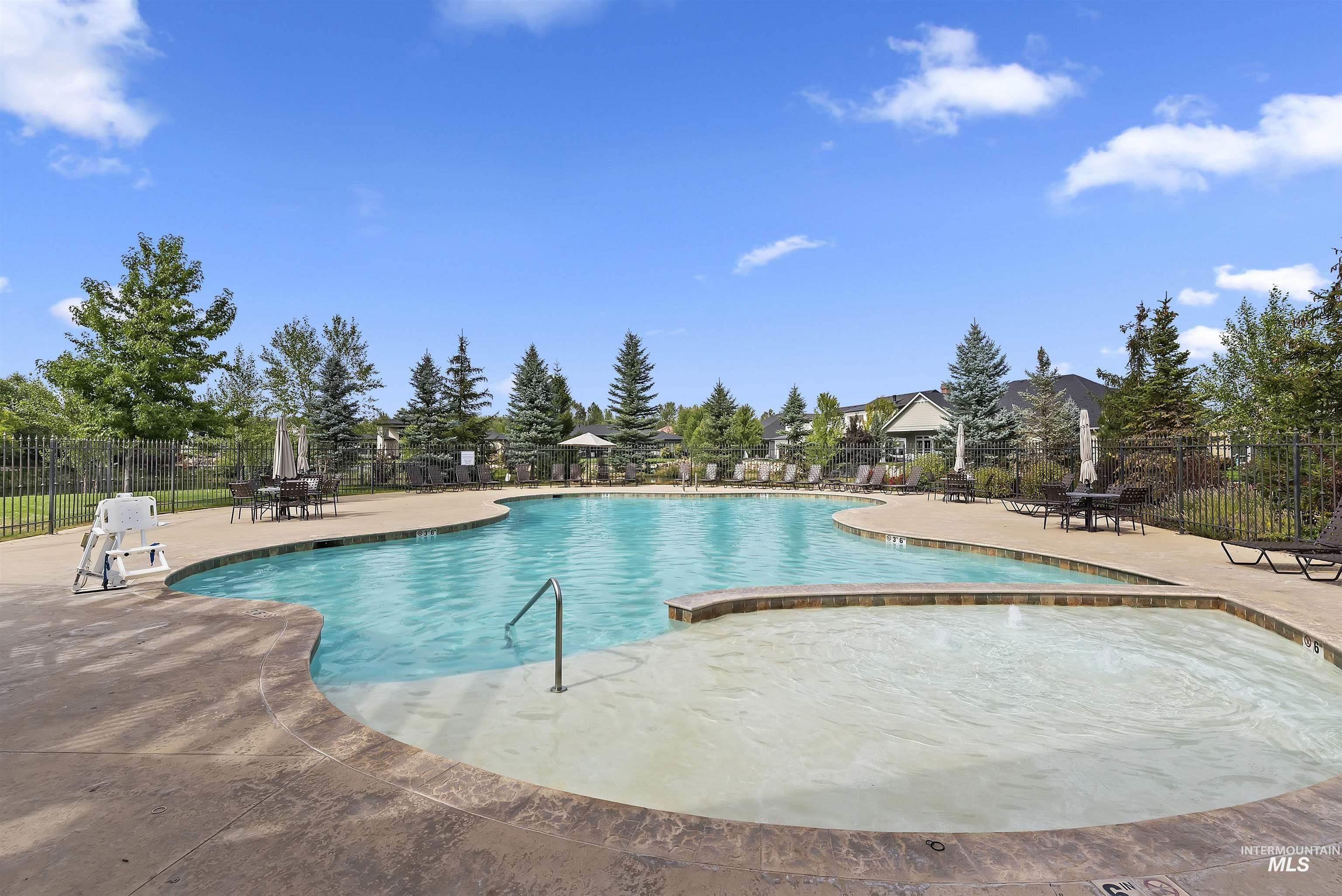 939 South Lake Pointe Way Eagle, ID 83616 - Photo 38 of 50 Resort-style pool area featuring a large main pool, integrated spa, surrounding stamped concrete decking, and mature evergreen landscaping