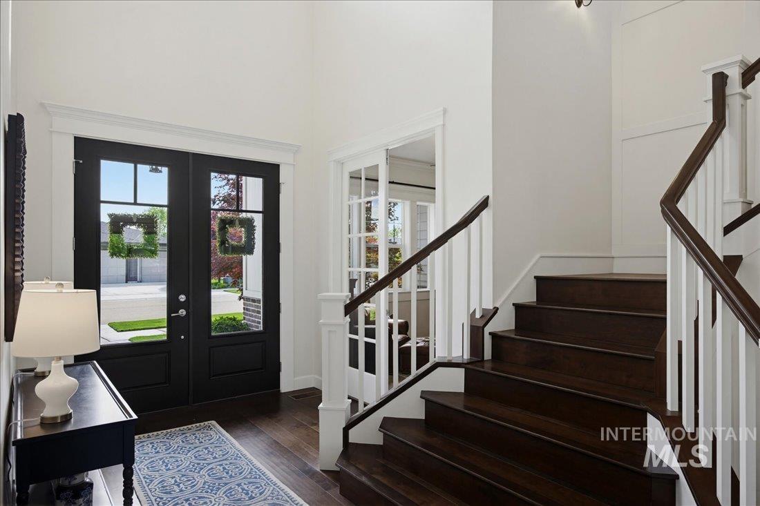 939 South Lake Pointe Way Eagle, ID 83616 - Photo 5 of 50 Two-story foyer featuring dark wood-finish flooring, a grand staircase with white risers and dark wood handrails, and a double-door entryway with transom windows