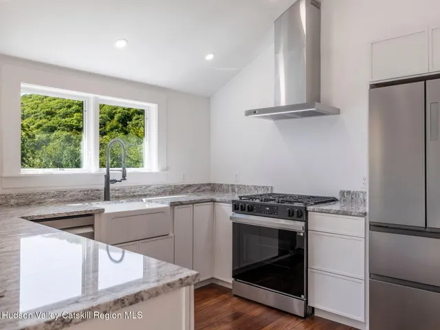 a view of an empty room with wooden floor and windows