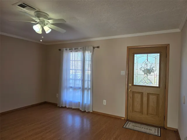 an empty room with wooden floor cabinet and windows