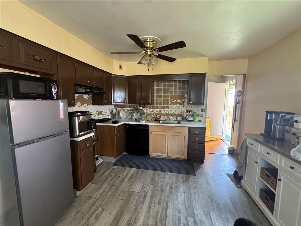 215 Maple Street Kittanning, PA 16201 - Photo 9 of 39 a kitchen with stainless steel appliances a stove a refrigerator a sink a microwave oven with cabinets and wooden floor
