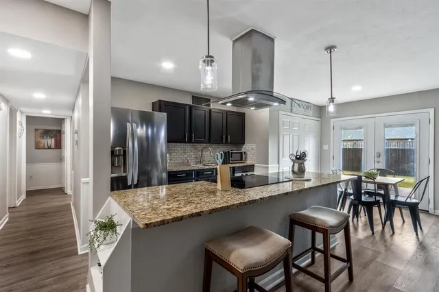 a kitchen with granite countertop a table chairs stove refrigerator and cabinets